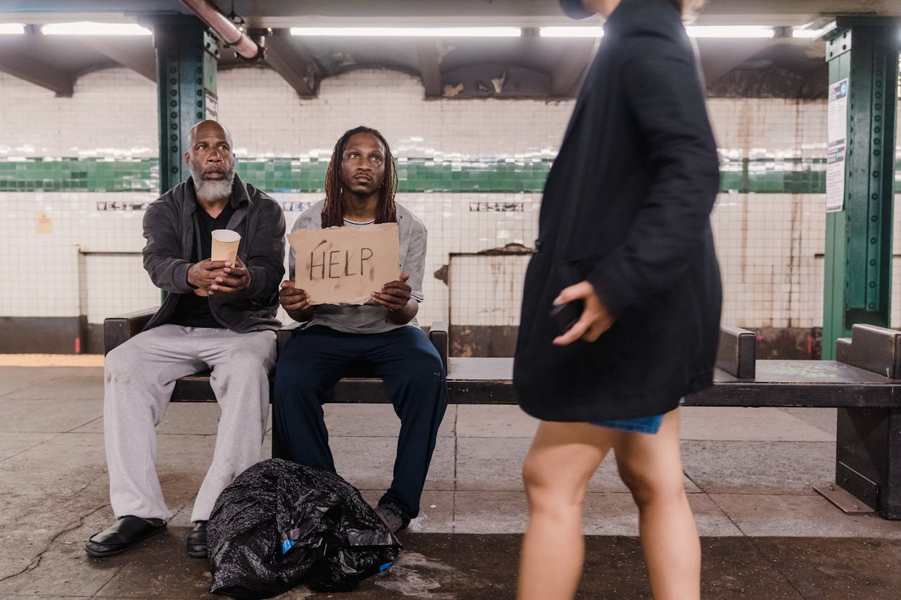 services-01 Two men seeking help at a subway platform, highlighting urban poverty and social issues.